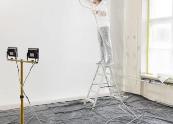 worker-painting-wall-ladder-full-shot